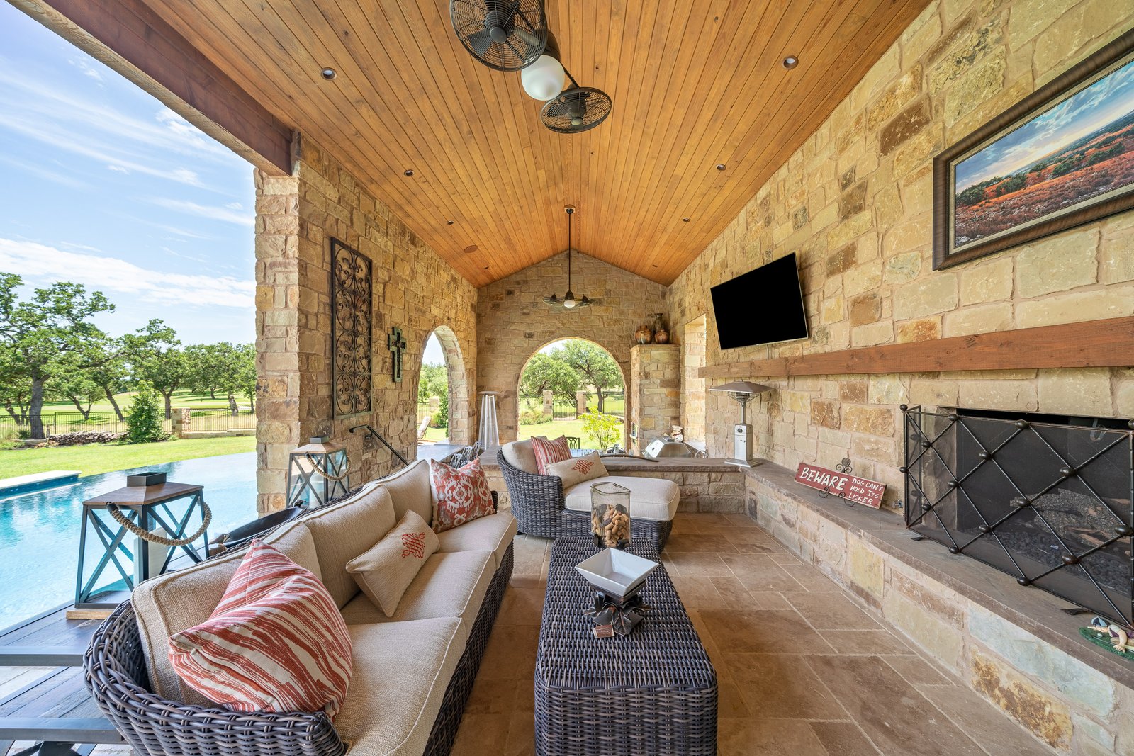 covered stone terrace with a fireplace, pool beside it